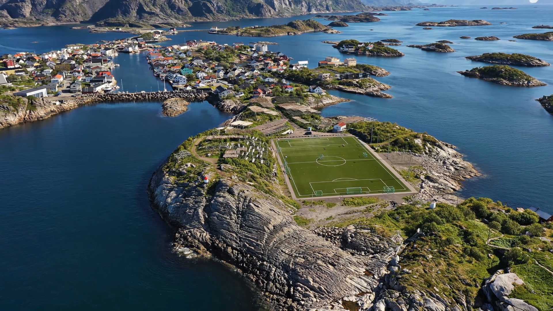 aerial view of a small islands with a football court in the middle and a small town seen near the small islands