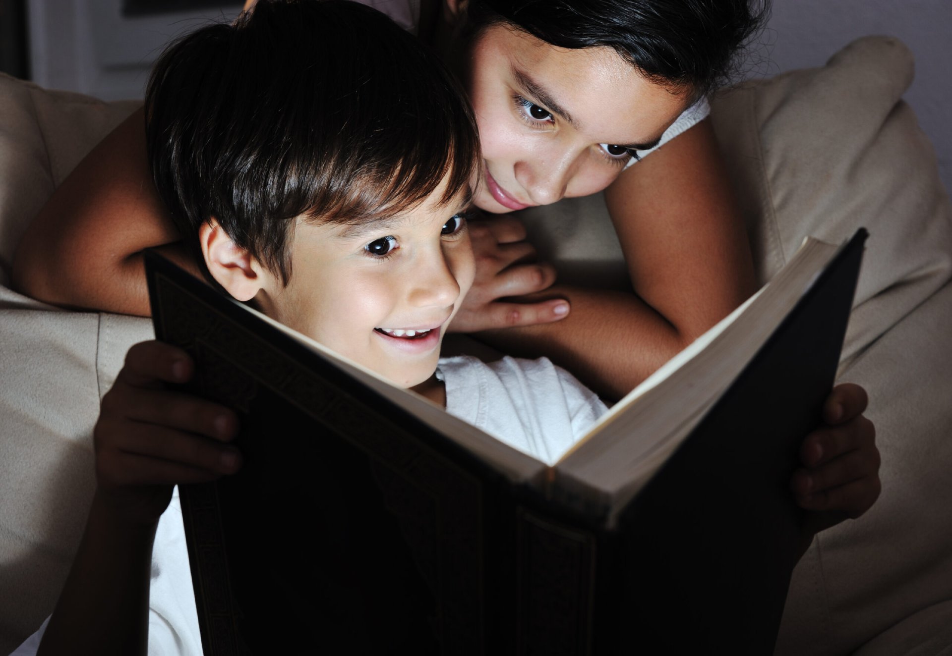 Boy and girl reading light book at night, children concept